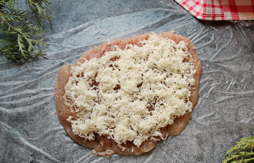 1. Этап. Куриный рулет с грибами, беконом и сыром: Сыр натрите на средней терке и половину разложите на филе.