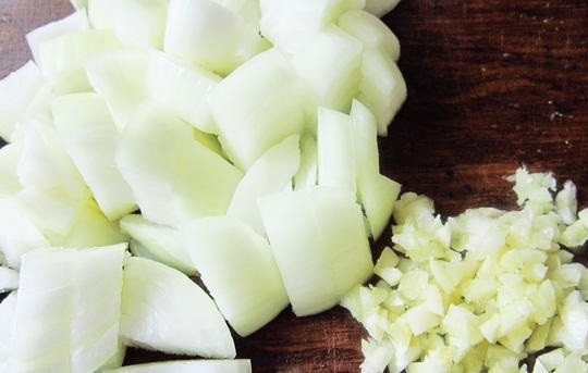 1. Этап. Свинина, тушеная со сливами: 2. Луковицы очищаем, моем и нарезаем крупными кусочками. Зубчики чеснока очищаем и мелко рубим ножом.