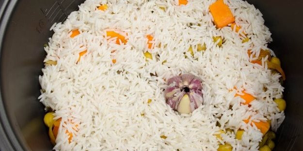 1. Этап. Плов с нутом в мультиварке: Через 5 минут засыпаем рис, вливаем кипяченую воду, солим. В серединку кладем головку чеснока, включаем режим 