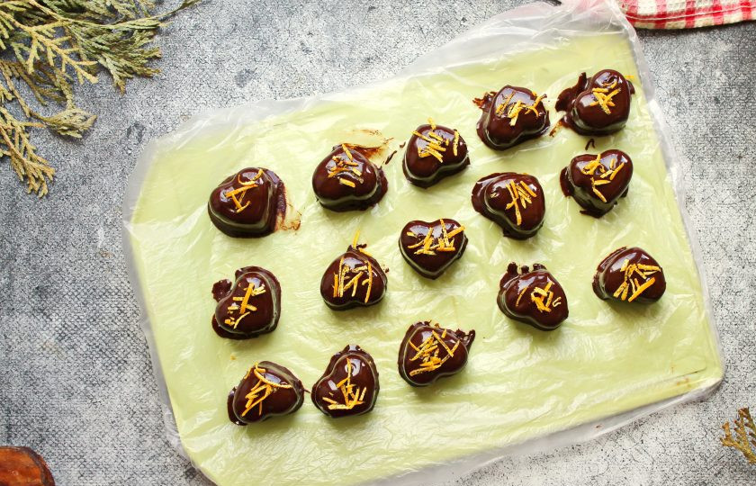 1. Этап. Апельсиновые конфеты: Извлеките из формы апельсиновую основу. Шоколад, у меня каллеты, растопите на водяной бане. Каждую апельсиновую часть окуните в шоколад и выложите на доску покрытую пленкой. Сверху каждую конфету посыпьте порезанной цедрой. Оставьте при комнатной температуре до застывания шоколада.