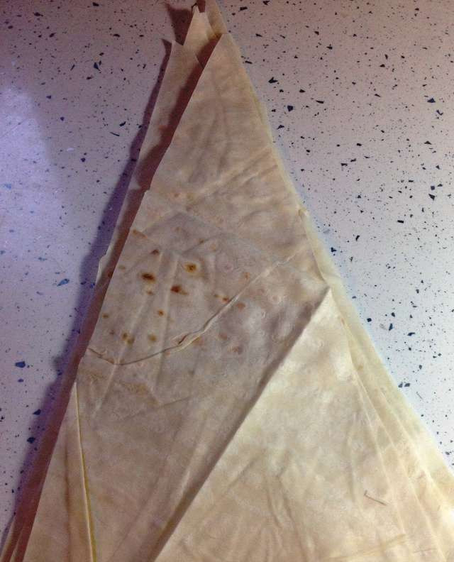 1. Этап. Сигары из лаваша: 2. В зависимости от размера листа лаваша, разрежьте его на 6-8 треугольников. Сложите получившиеся листы в стопочку и накройте пленкой. Доставайте по одному, чтобы лаваш не сох.