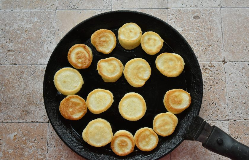 1. Этап. Дутые оладьи: Перед порционированием теста на сковороду, отрежьте кончик кондитерского мешка. Давите тесто сверху, придерживая кондитерский мешок снизу. Закончив выдавливать нужную порцию, одновременно прекращайте давить одной рукой и приподнимайте носик мешка другой, чтобы тесто прекратило вытекать.