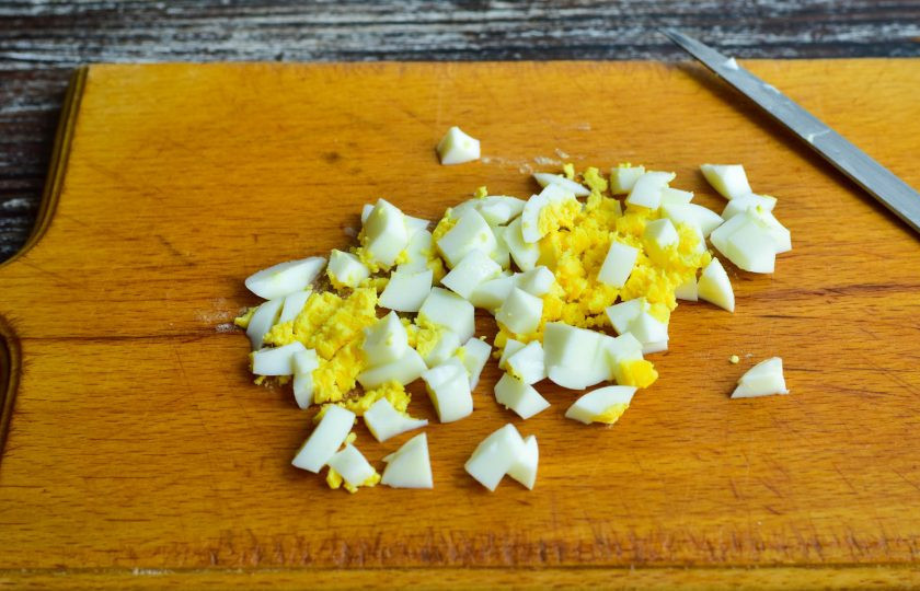 1. Этап. Салат с кальмарами, креветками и ананасами: Нарежьте вареное куриное яйцо.