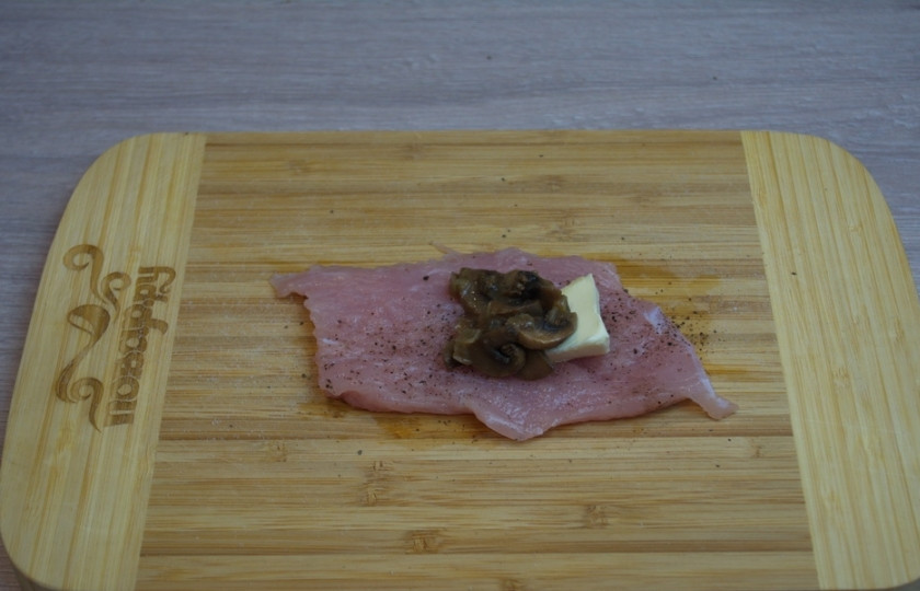 1. Этап. Котлеты по-киевски с грибами: Мясо отбейте молоточком. Посолите, поперчите. На край пласта мяса уложите кусочек сливочного масла. Добавьте немного обжаренных грибов.