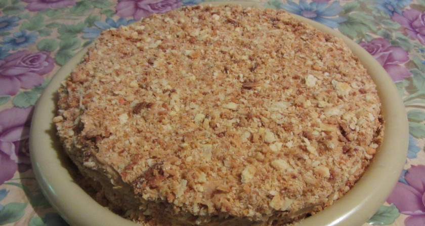 1. Этап. Наполеон из слоеного теста со сгущенкой: 4. Смажем теперь коржи кремом и склеим между собой. Обрезаем их по кругу, придавая торту форму, а обрезки измельчим. Смажем кремом торт по всей поверхности и с боков, после чего обильно посыпаем крошкой.