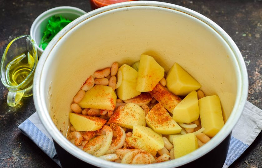 1. Этап. Картошка с фасолью в мультиварке: В чашу мультиварки выложите картофель, лук и фасоль. Добавьте специи.