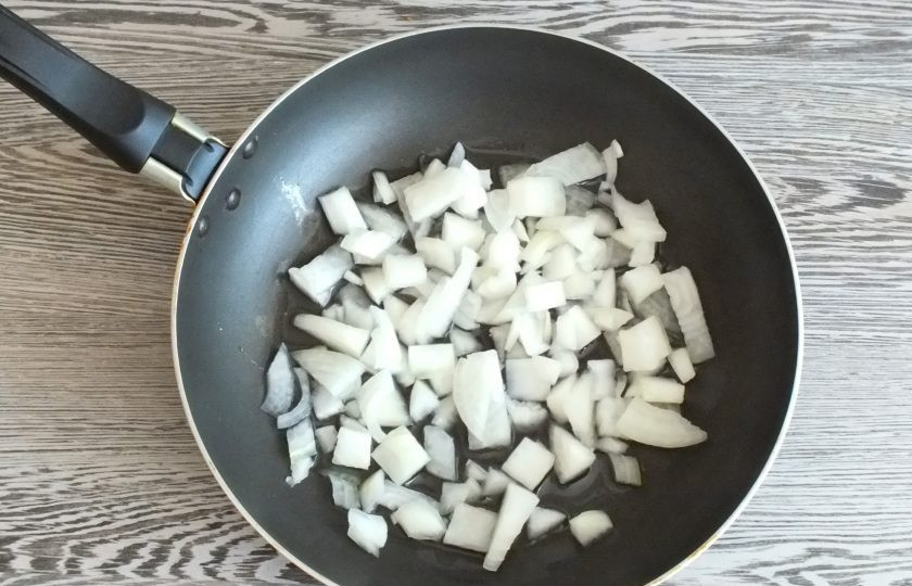 1. Этап. Треска запеченная с солеными огурцами: Репчатый лук нарежьте произвольно. В сковороде разогрейте растительное масло, переложите лук. Обжарьте до румяности.