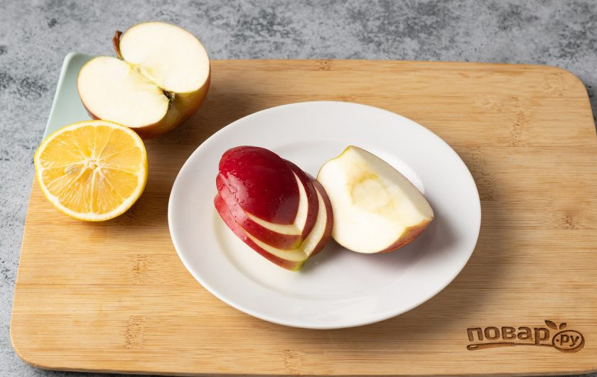 1. Этап. Фруктовая нарезка Дракон на Новый год: Яблоко разрежьте на 4 части, удалите сердцевину. Из двух четвертинок сделайте ушки дракона. Для этого вырежьте углубление, в форме ромба, как на фото, затем еще одно. Повторите со второй четвертинкой. Все части яблока обязательно сбрызгивайте лимонным соком, чтобы они не темнели.