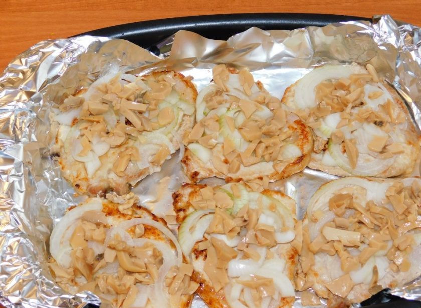 1. Этап. Свиные отбивные с овощами под сыром в духовке: Обжарьте на сильном огне немного и выложите в форму для запекания. Сверху выложите нарезанный лук и шампиньоны.