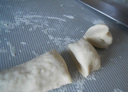 1. Этап. Вареники с картошкой постные: 2. В миску налейте воду, доведите ее до кипения и добавьте соль, затем — 120 грамм муки, энергично перемешивайте ложкой, затем порционно подсыпайте оставшуюся муку. Замесите тесто и оберните пленкой, оставьте на 10 минут. Разделите его на части и сверните колбаску, затем нарежьте ее кусочками.