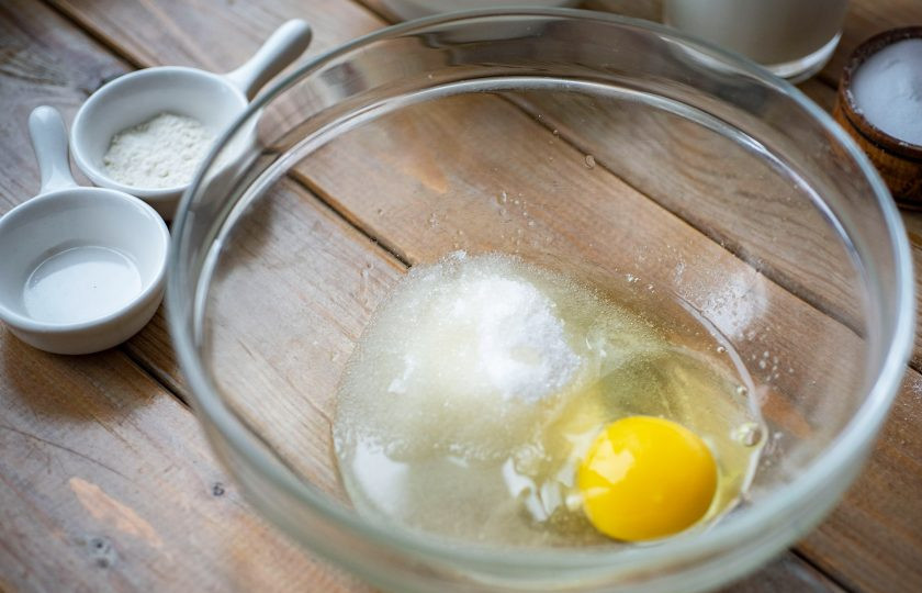 1. Этап. Панкейки на йогурте пышные: В просторную миску влейте растительное масло, вбейте яйцо, добавьте сахар. Венчиком перемешайте эти ингредиенты.