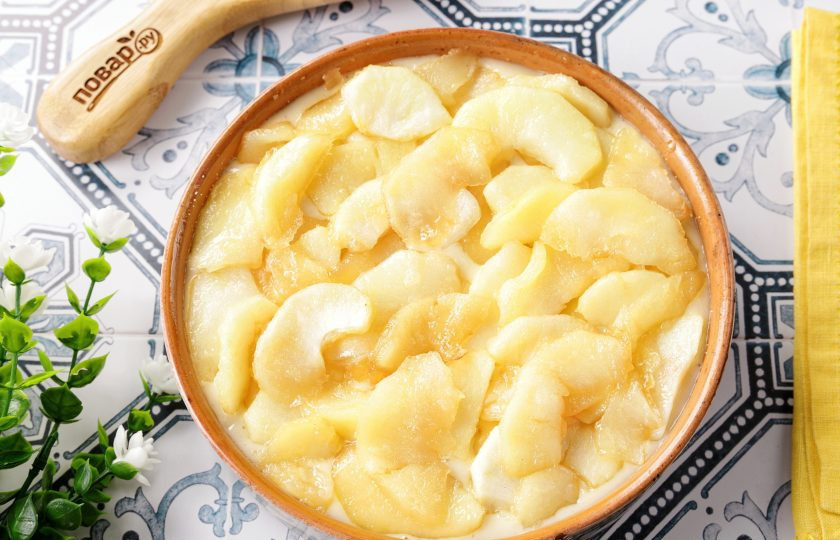 1. Этап. Шарлотка с яблоками в аэрогриле: Жаропрочную форму смажьте маслом. Дно присыпьте мукой или манкой. Вылейте тесто и сверху выложите произвольно карамелизованные яблоки. У меня глиняная форма, можете взять другую, но самое главное — она должна быть достаточно высокая т.к. пирог будет расти.