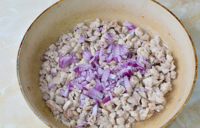 1. Этап. Блины купеческие: Для приготовления начинки мелко нарежьте курицу и обжарьте её в течение 10-12 минут. Затем добавьте мелко нарезанный красный лук. Обжаривайте курицу с луком еще 2-3 минуты.