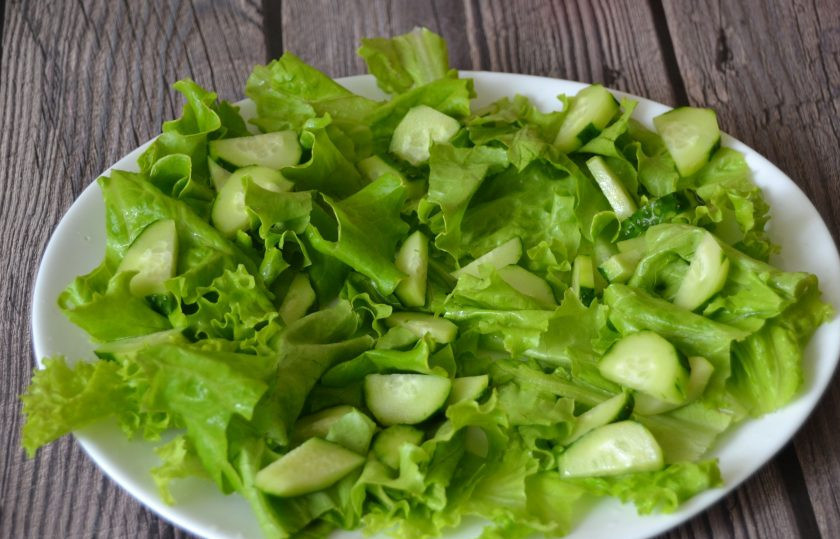 1. Этап. Овощной салат с тунцом: Руками нарвите листья салата, выложите на дно тарелки. Нарежьте огурцы дольками, уложите поверх салатных листьев.