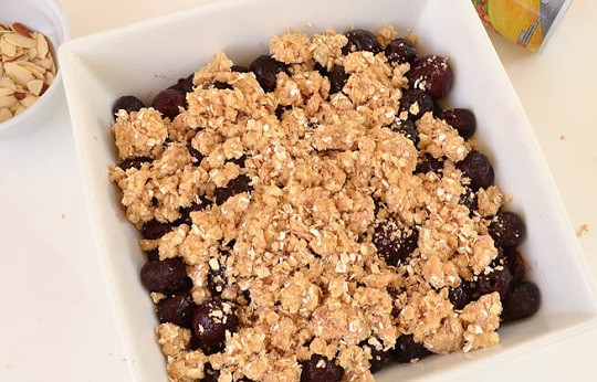 1. Этап. Овсяный крамбл: 6. Жаропрочную форму смажьте немного маслом, выложите в неё ягоды. Сверху присыпьте все крошкой, распределив её равномерно.