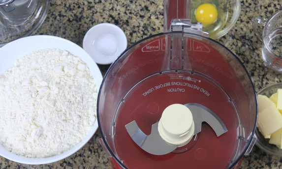 1. Этап. Эмпанадас с говядиной: 1. Первым делом замесите тесто. Соедините растопленное сливочное масло, яйцо, воду, соль и просеянную муку. Вымешайте, скатайте в шарик и оберните пищевой пленкой.