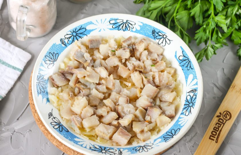 1. Этап. Селедка под шубой с мандаринами: Нарежьте мелкими кубиками слабосоленую сельдь (филе или кусочки из пресервы). Выложите на слой картофеля.