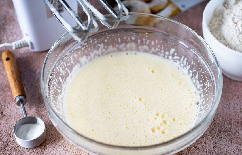 1. Этап. Пончики в мультипекаре: Залейте растопленное масло в миску ко взбитым с сахаром яйцам и при этом продолжайте взбивать миксером, вмешивая масло.