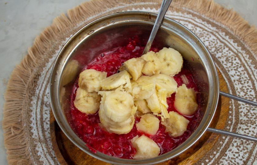 1. Этап. Красная смородина с бананом на зиму: Бананы нарежьте на кусочки и добавьте в кастрюлю к ягодам. Аккуратно перемешайте. Поставьте на плиту и варите при среднем нагреве до кипения.