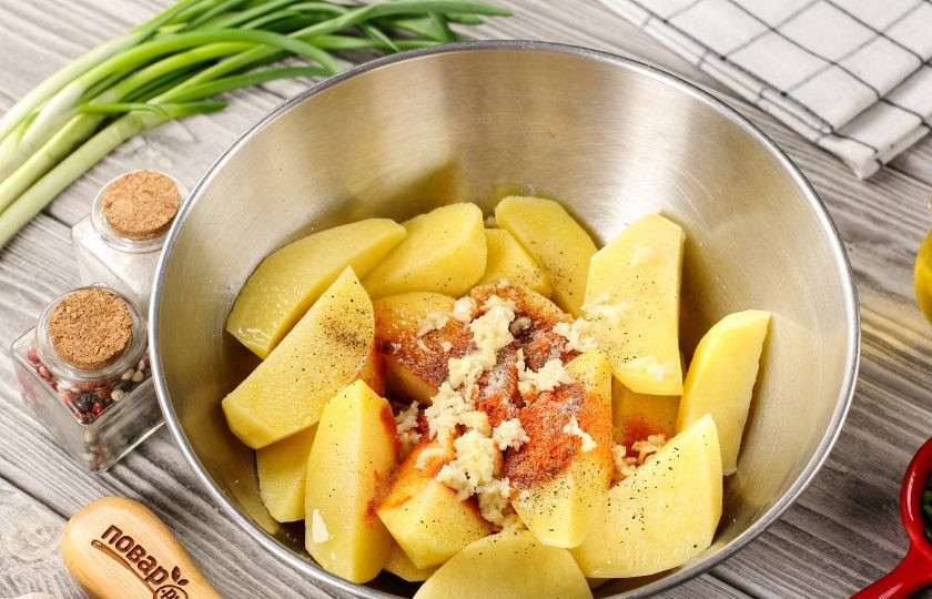 1. Этап. Картофельные дольки с сыром в духовке: Добавьте к картофелю давленый чеснок, растительное масло, соль и специи по вкусу.