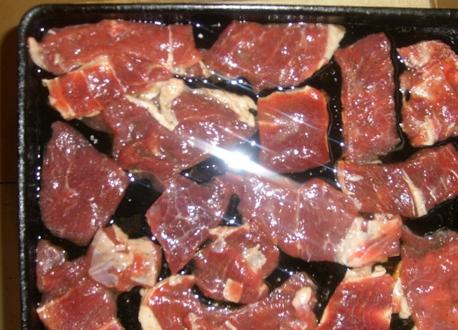 1. Этап. Говядина по-французски в духовке: Теперь смазываем противень маслом и раскладываем на нем говядину.