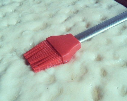 1. Этап. Фокачча тонкая: Сделайте на тесте пальцами небольшие вмятинки по всему периметру. Остаток масла смешайте с таким же количеством воды и смажьте тесто сверху. Присыпьте крупной солью.