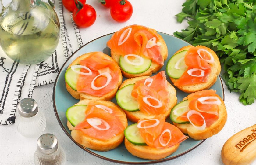 1. Этап. Брускетты в аэрогриле: Нарежьте белую или зеленую части лука по диагонали и выложите на семгу. Можно использовать репчатый лук или красный.