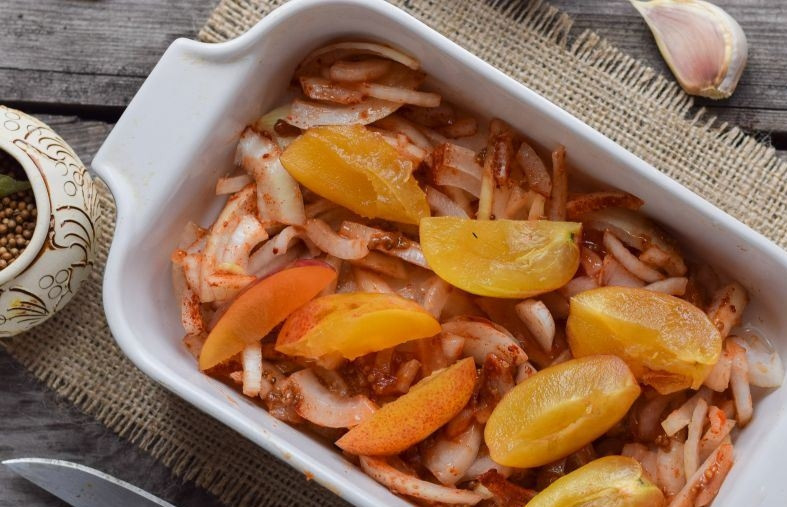 1. Этап. Печень цыплят бройлеров: Смажьте форму для запекания растительным маслом, выложите в нее замаринованный лук. Сливы вымойте, освободите от косточек и нарежьте на дольки. Выложите сливы на лук.