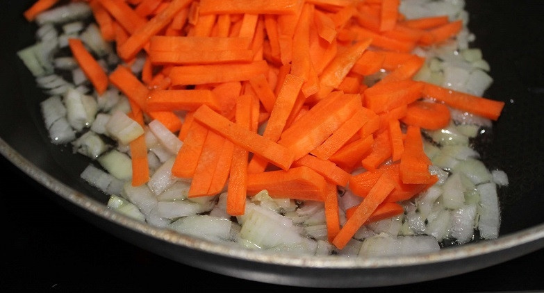 1. Этап. Борщ сибирский с мясом: 4. Морковку нарежьте тонкими ломтиками и добавьте к луку. Огонь уменьшите и жарьте, немного помешивая.