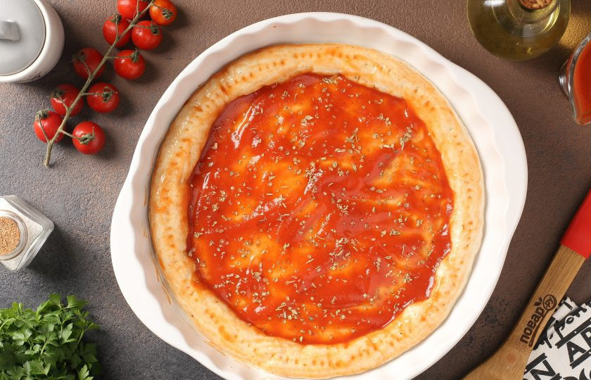 1. Этап. Пицца из дрожжевого теста холодного приготовления: Смажьте соусом и посыпьте орегано.