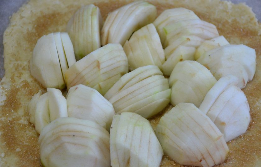 1. Этап. Бретонский яблочный пирог: Выложите на тесто яблоки, сохраняя форму четвертинок, порезанных ломтиками. Подверните края теста, помогая себе пергаментом.