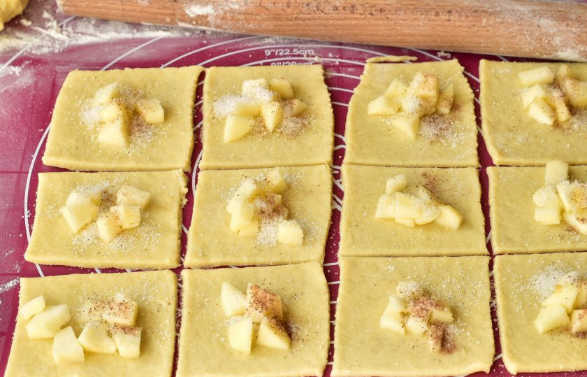 1. Этап. Печенье Творожные платочки: Выложите яблоко, которое нарежьте кусочками. Сверху посыпьте сахаром и корицей.