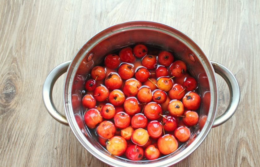 1. Этап. Маринованные ранетки на зиму: Влейте в кастрюлю воду и доведите до кипения на среднем огне. Выложите ранетки в кастрюлю и прогрейте на медленном огне в течение 4 минут. Яблоки не мешайте, а лишь немного притапливайте их ложкой.