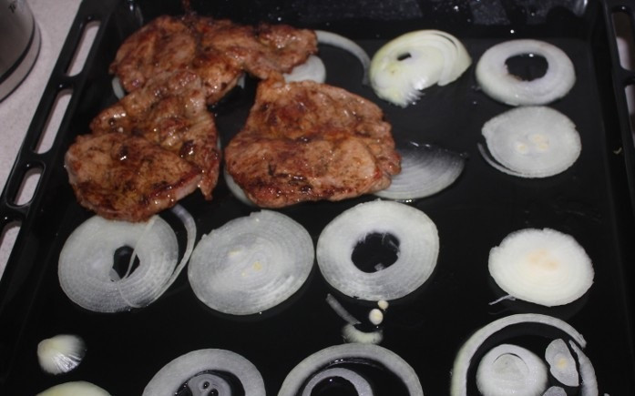 1. Этап. Свинина в соевом соусе в духовке: 7. Тем временем можно очистить и нарезать средними полукольцами луковицу. При желании ее можно немного подсолить и поперчить. Противень смазать немного маслом и выложить на дно лук. Затем, по мере обжаривания, выкладывать кусочки свинины.