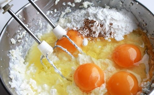 1. Этап. Новогодний чизкейк с клюквой: 5. Вбейте яйца, добавьте кукурузный крахмал, щепотку соли и мускатный орех. Продолжайте взбивать, пока масса не станет однородной и воздушной.