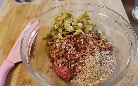 1. Этап. Фаршированные грибы с оливками и орехами: К говяжьему фаршу добавьте оливки, орехи и пшеничные отруби. Посолите, поперчите и хорошо все перемешайте.