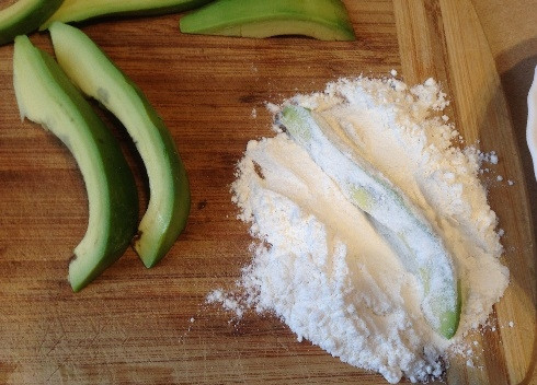 1. Этап. Авокадо во фритюре: На доску выложим оставшуюся муку, смешаем ее со щепоткой соли. Со всех сторон обваливаем кусочки авокадо в муке.