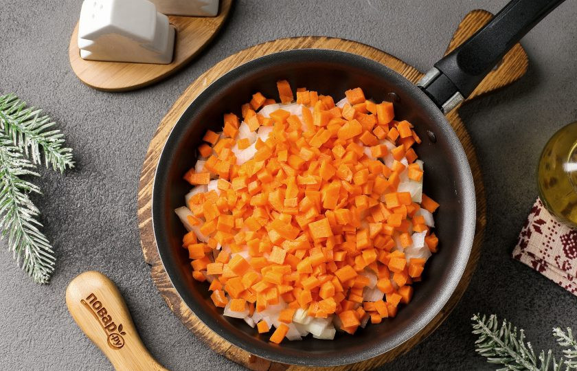 1. Этап. Сырный крем-суп с грибами в хлебе Веселый Кролик: Лук и морковь нарежьте кубиками и переложите в разогретую сковороду с маслом. Обжарьте овощи до мягкости.