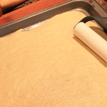 1. Этап. Пицца Калифорния: Раскатываем тесто на противне, слегка смазанном маслом.