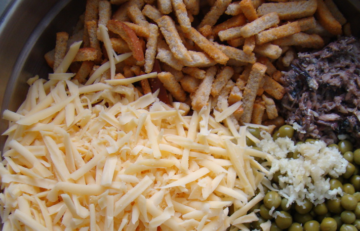 1. Этап. Салат со шпротами и сыром: В глубокой миске соединяем: шпроты, тертый сыр, зеленый горошек, пропущенный через пресс чеснок и сухарики.