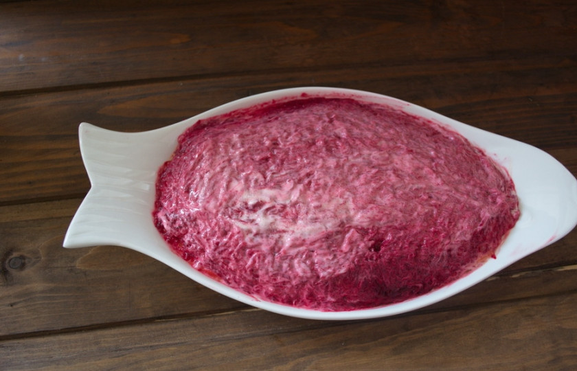 1. Этап. Селедка под шубой классический рецепт: Отварную крупную свеклу натрите на мелкой терке. Выложите следующим слоем. Посолите, смажьте майонезом. Хорошо распределите майонез по всему салату мокрой ложкой. Так салат равномерно пропитается и будет вкуснее. Поставьте салат в холод на пару часов.