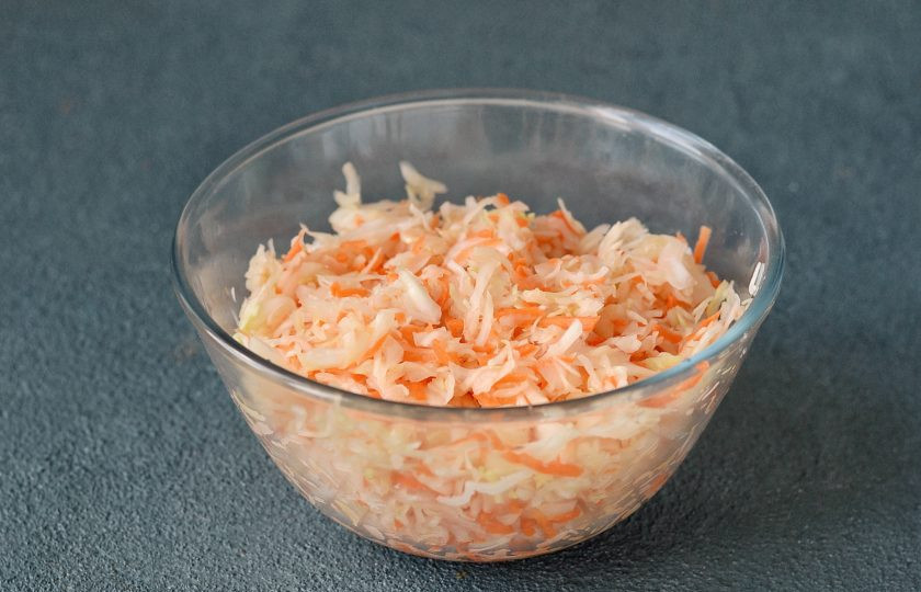 1. Этап. Квашеная капуста с клюквой и яблоками: Добавьте соль и сахар. Перемешайте и разомните руками.