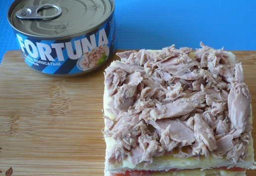 1. Этап. Сэндвичи Рождественские елки с тунцом: На картофельное пюре первым слоем выложите нарезанные кусочки форели. Затем накройте другим ломтиком хлеба, выложите снова слой картофеля и на него консервированного тунца.