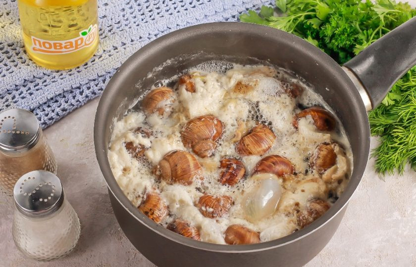 1. Этап. Виноградные улитки по-бургундски: Улитки промойте в воде и выложите в глубокую емкость: кастрюлю, ковш или казан. Влейте горячую воду и поместите емкость на плиту. Доведите до кипения и отварите 2-3 минуты. За это время выделится очень много пены, слейте воду, промойте улиток в воде.