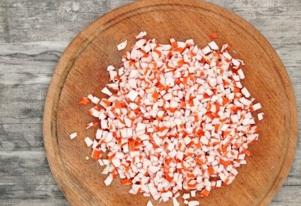 1. Этап. Слоеный салат с крабовыми палочками: 3. Крабовые палочки очистите и нарежьте мелкими кубиками. Если вы хотите, чтобы слоеный салат с крабовыми палочками в домашних условиях был более нежным, можете натереть их на терке.