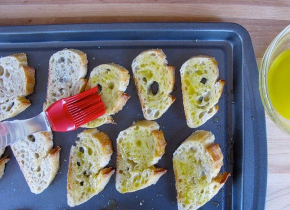 1. Этап. Бутерброды с семгой: 2. Соедините растопленное сливочное и оливковое масло. Смажьте хлеб с помощью кисточки и выложите на противень. Отправьте в разогретую до 200 градусов духовку.