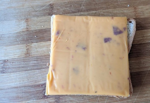 1. Этап. Сэндвич «Патти Мелт» с индейкой: Собираем сэндвич. Тостовый хлеб смазываем оставшимся сливочным маслом с обеих сторон. Кладём ломтик сыра. В оригинале - грюйер. У меня плавленый сыр с добавками.