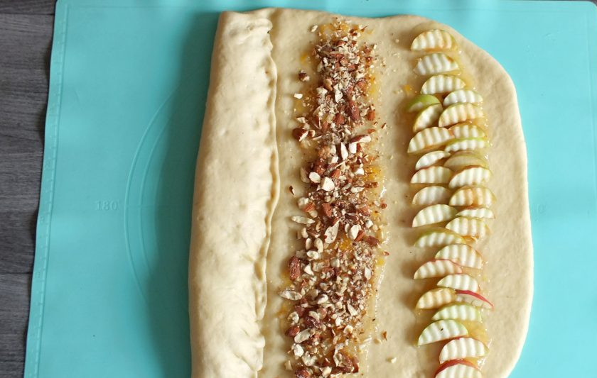 1. Этап. Дрожжевой пирог с яблоками и изюмом: Свободным краем пласта накройте полосу с изюмом. Прижмите тесто пальцами.