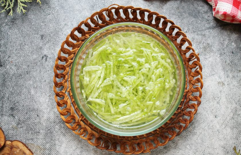 1. Этап. Салат из редьки с жареным мясом: Редьку вымойте, почистите от кожуры и натрите на терке для корейской моркови. Положите редьку в чашку и залейте холодной водой на 10-15 минут. Спустя время откиньте редьку на сито, дайте воде стечь, а затем отожмите от остатков воды.