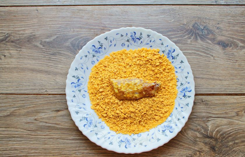 1. Этап. Куриные нагетсы в кукурузной панировке в духовке: Кукурузные хлопья измельчите в крошку и запанируйте в них нагетсы.